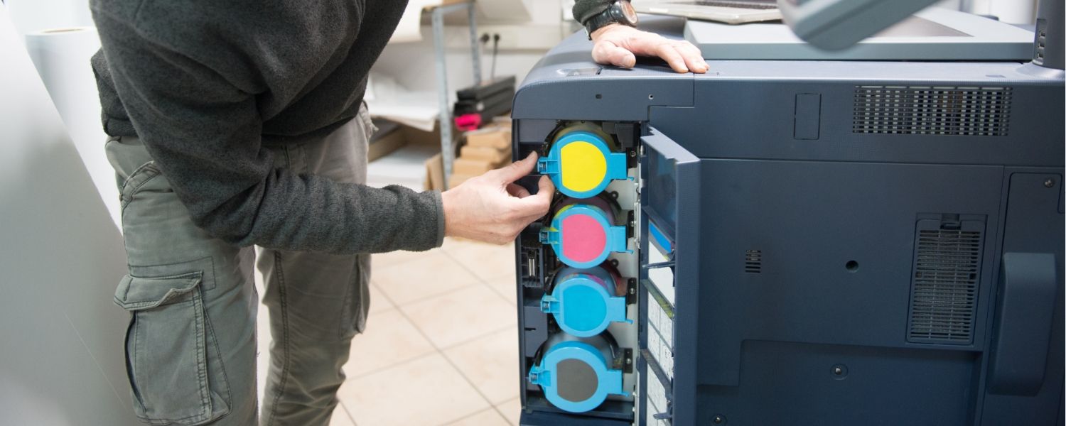Ein IT-Techniker wartet einen Multifunktionsdrucker und tauscht die Tomer aus.